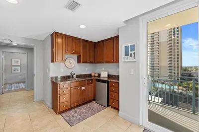 a kitchen with wooden cabinets and a large window at Sterling Breeze 607 | Gulf-Front 3BR Condo | 6th Floor Balcony, Infinity Pool, Direct Beach Access in Panama City Beach