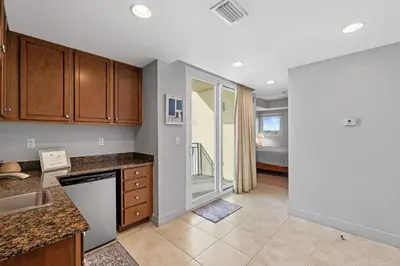 a kitchen with wooden cabinets and a living room at Sterling Breeze 607 | Gulf-Front 3BR Condo | 6th Floor Balcony, Infinity Pool, Direct Beach Access in Panama City Beach