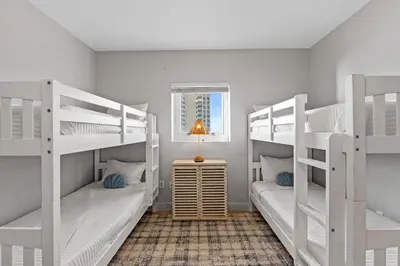 a room with two bunk beds and a lamp at Sterling Breeze 607 | Gulf-Front 3BR Condo | 6th Floor Balcony, Infinity Pool, Direct Beach Access in Panama City Beach