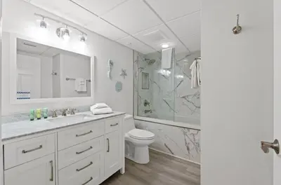 a white bathroom with a toilet and a shower at Emerald Beach 1736 by Emerald Coast Retreats in Panama City Beach