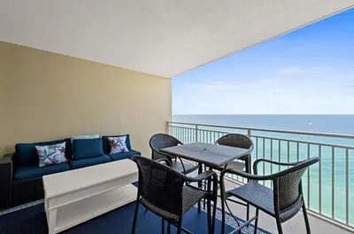 a balcony with a couch and chairs and the ocean at Emerald Beach 1736 by Emerald Coast Retreats in Panama City Beach