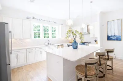 a kitchen with white cabinets and a white island with stools at Second Star Shores in Watersound Beach
