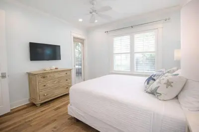 a white bedroom with a bed and a tv at Second Star Shores in Watersound Beach
