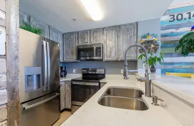 a kitchen with a sink and a stainless steel refrigerator at Seychelles 407 in Panama City Beach