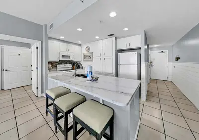 a kitchen with white cabinets and a large island with stools at Sterling Reef 104 in Panama City Beach