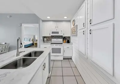 a white kitchen with white cabinets and a sink at Sterling Reef 104 in Panama City Beach