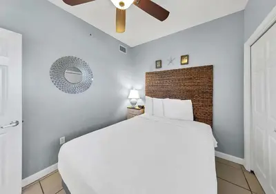 a bedroom with a white bed and a ceiling fan at Sterling Reef 104 in Panama City Beach