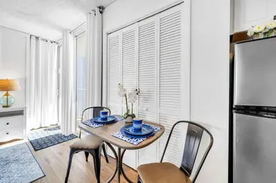 a dining room with a table and chairs and a refrigerator at Long Beach Resort 1-1300E in Panama City Beach