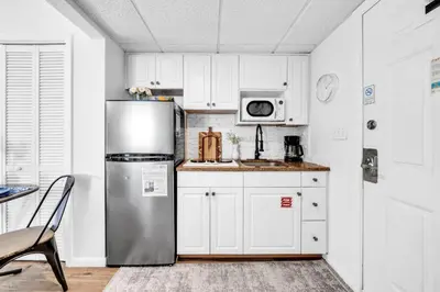 a kitchen with a stainless steel refrigerator and white cabinets at Long Beach Resort 1-1300E in Panama City Beach