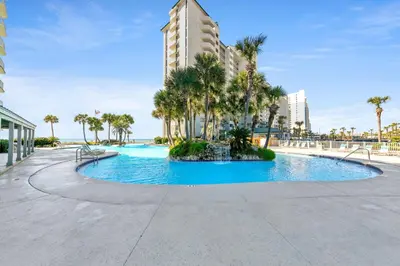 a swimming pool with palm trees and a tall building at Long Beach Resort 1-1300E in Panama City Beach