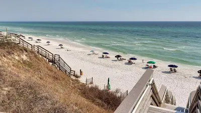 a beach with umbrellas and people sitting on the sand at Salty Seabreeze in Seacrest