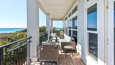 a balcony with chairs and tables and the ocean at Camelot in Seagrove Beach