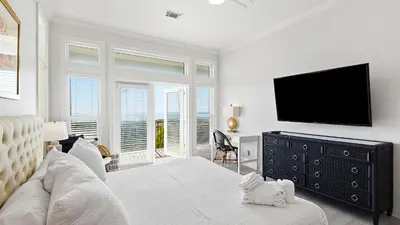 a white bedroom with a television and a dresser at Camelot in Seagrove Beach