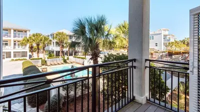 a balcony with a view of a pool and palm trees at Camelot in Seagrove Beach