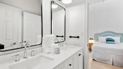 a white bathroom with a sink and a bed at Camelot in Seagrove Beach