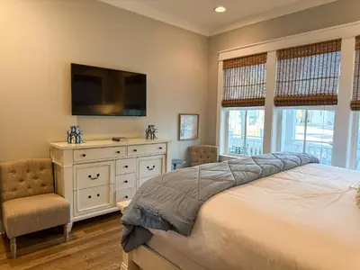 a bedroom with a bed and a tv and a chair at Bella Sol by 30A Escapes in Rosemary Beach