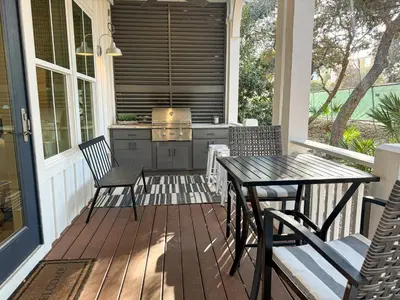 a porch with a table and chairs and a kitchen at Bella Sol by 30A Escapes in Rosemary Beach