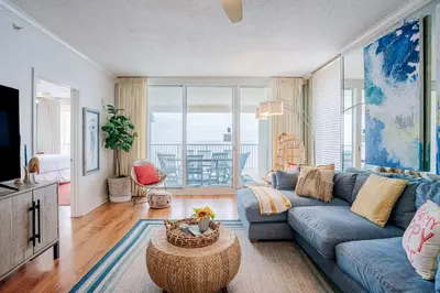 a living room with a blue couch and a large window at Majestic Sunset For 11 in Panama City Beach