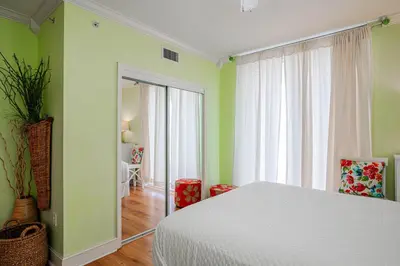 a bedroom with a white bed and green walls at Majestic Sunset For 11 in Panama City Beach