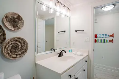 a white bathroom with a sink and a mirror at Majestic Sunset For 11 in Panama City Beach