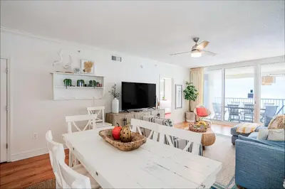 a living room with a table and a television at Majestic Sunset For 11 in Panama City Beach