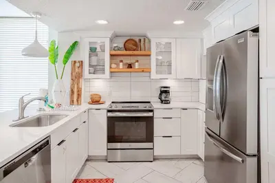 a kitchen with white cabinets and a stainless steel refrigerator at Majestic Sunset For 11 in Panama City Beach