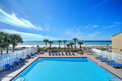 a pool with chairs and the ocean in the background at Resort Townhome with Free Golf Cart in Panama City Beach