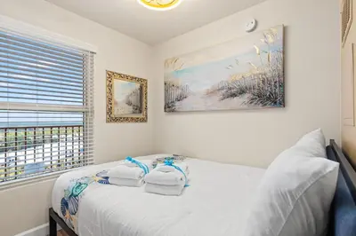 a white bedroom with two towels on a bed at Come visit Sophomore! 2BR 2BA Beachfront Condo! Sleeps 5! in Panama City Beach