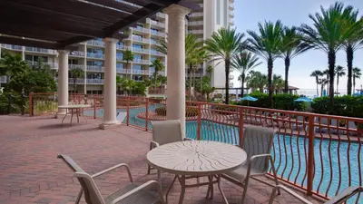 a patio with a table and chairs next to a pool at Come visit Sophomore! 2BR 2BA Beachfront Condo! Sleeps 5! in Panama City Beach
