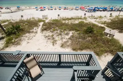 a deck with two chairs and a beach with umbrellas at Seagull Villas #7 by Emerald Coast Retreats in Panama City Beach