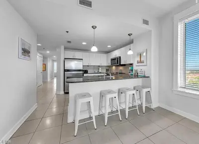 a kitchen with white cabinets and a bar with stools at Sandy Feet Retreat 3 bed 3 bath in Panama City Beach