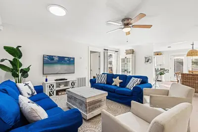 a living room with blue couches and a tv at Laguna Breeze! Dog-Friendly 4BR Beach Escape for 8 with Coastal Charm! in Panama City Beach