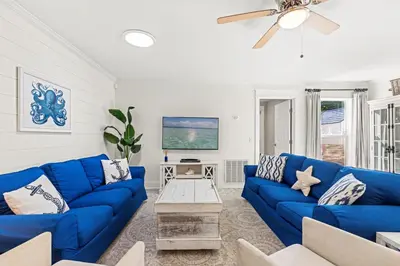 a living room with blue couches and a ceiling fan at Laguna Breeze! Dog-Friendly 4BR Beach Escape for 8 with Coastal Charm! in Panama City Beach