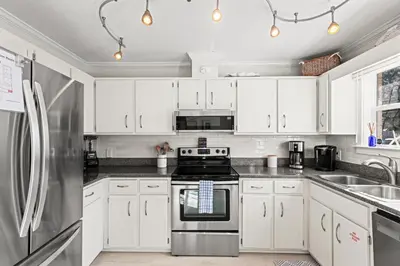 a kitchen with white cabinets and a stove at Laguna Breeze! Dog-Friendly 4BR Beach Escape for 8 with Coastal Charm! in Panama City Beach