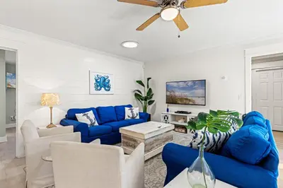a living room with blue couches and a ceiling fan at Laguna Breeze! Dog-Friendly 4BR Beach Escape for 8 with Coastal Charm! in Panama City Beach