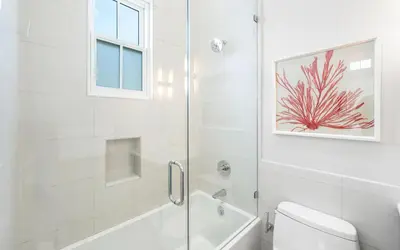 a white bathroom with a shower and a toilet at Sealah in Rosemary Beach