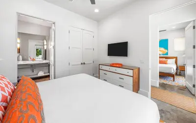 a white bedroom with a bed and a television at Sealah in Rosemary Beach