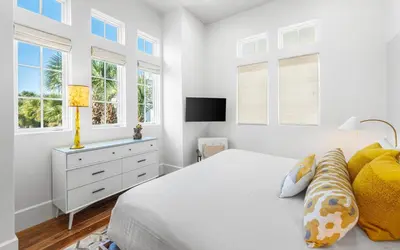 a white bedroom with a bed and windows at Sealah in Rosemary Beach