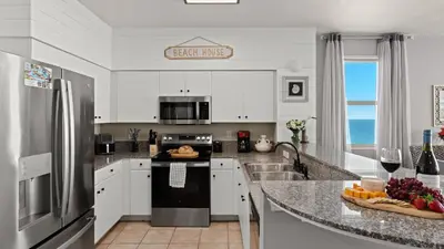 a kitchen with white cabinets and a granite counter top at Emerald Horizon by AvantStay Beachfront Condo Resort Pool Gulf Balcony Views Near Pier Park Dining in Panama City Beach