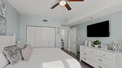 a bedroom with a white bed and a ceiling fan at Emerald Horizon by AvantStay Beachfront Condo Resort Pool Gulf Balcony Views Near Pier Park Dining in Panama City Beach