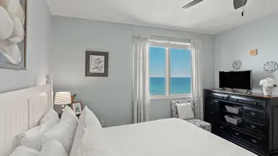 a bedroom with a bed and a window with the ocean at Emerald Horizon by AvantStay Beachfront Condo Resort Pool Gulf Balcony Views Near Pier Park Dining in Panama City Beach