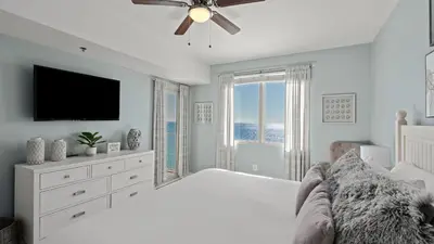 a white bedroom with a bed and a television at Emerald Horizon by AvantStay Beachfront Condo Resort Pool Gulf Balcony Views Near Pier Park Dining in Panama City Beach