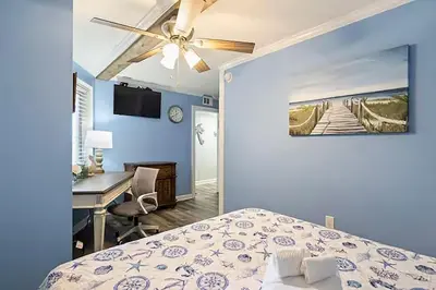 a bedroom with a bed with a ceiling fan and a desk at Moondrifter 205 in Panama City Beach