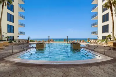 a swimming pool in a resort with the ocean in the background at Origin 0933 - Studio King - Sunrise Gulf Views in Panama City Beach