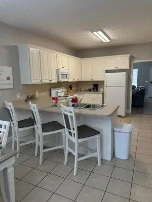 a kitchen with white cabinets and a counter with chairs at Beach Days, Nightlife Nights, East End of PCB in Panama City Beach