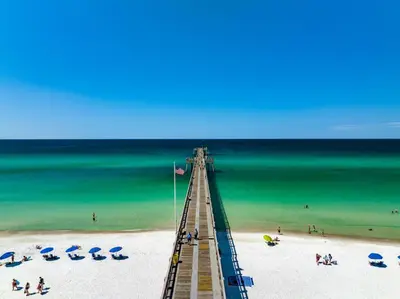 a pier on a beach with umbrellas and the ocean at Pet Friendly Beach House - Tropic Like It's Hot in Panama City Beach