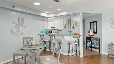 a kitchen with a bar with stools and a table at Emerald Lagoon by AvantStay Bright Condo Pool Pier Tennis Access Walk to Beach Dining in Panama City Beach