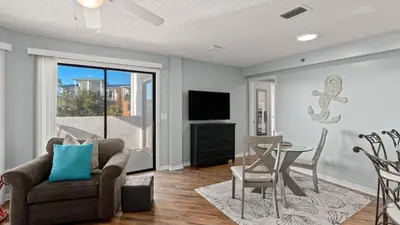 a living room with a couch and a table and a television at Emerald Lagoon by AvantStay Bright Condo Pool Pier Tennis Access Walk to Beach Dining in Panama City Beach