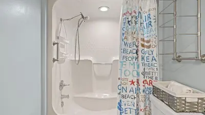 a bathroom with a shower curtain and a toilet at Emerald Lagoon by AvantStay Bright Condo Pool Pier Tennis Access Walk to Beach Dining in Panama City Beach