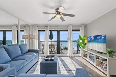 a living room with a blue couch and a ceiling fan at Commodore 0403 in Panama City Beach